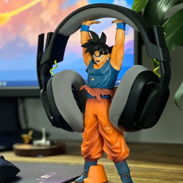 Brightly colored Goku figurine is holding headphones on a modern gaming desk