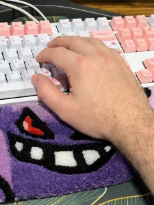 Uma mão está apoiada em um tapete de teclado fofo da Standify com o Gengar